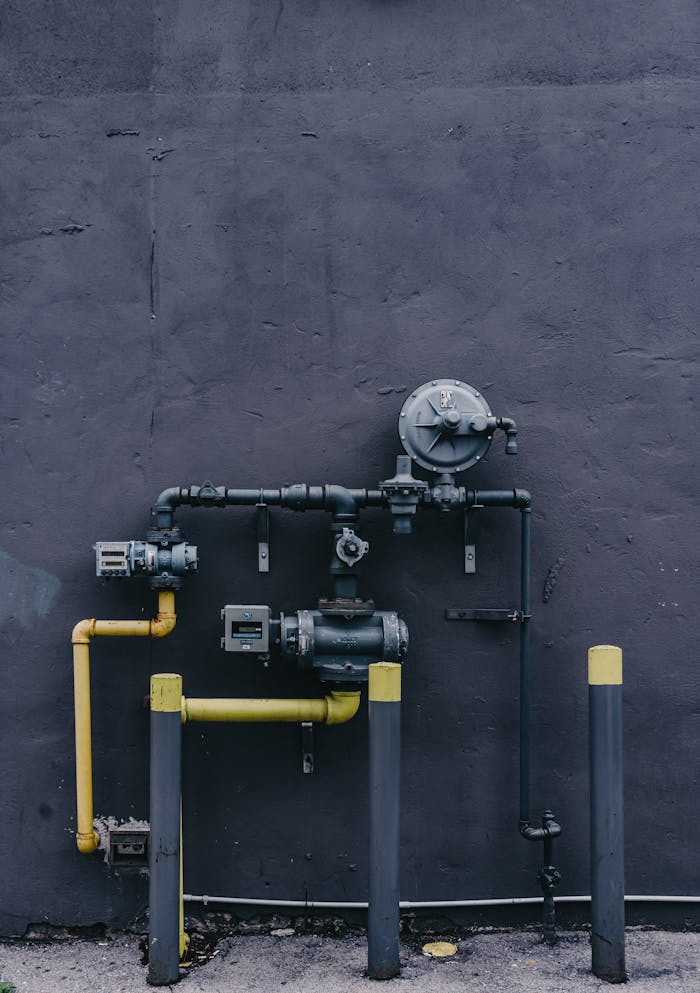 why-choose-us Pipes and machinery against an urban building wall with a gritty industrial look.