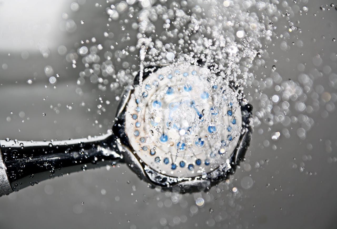 our-services-1 Close-up of a shower head releasing water droplets, creating a crisp and refreshing bathroom scene.